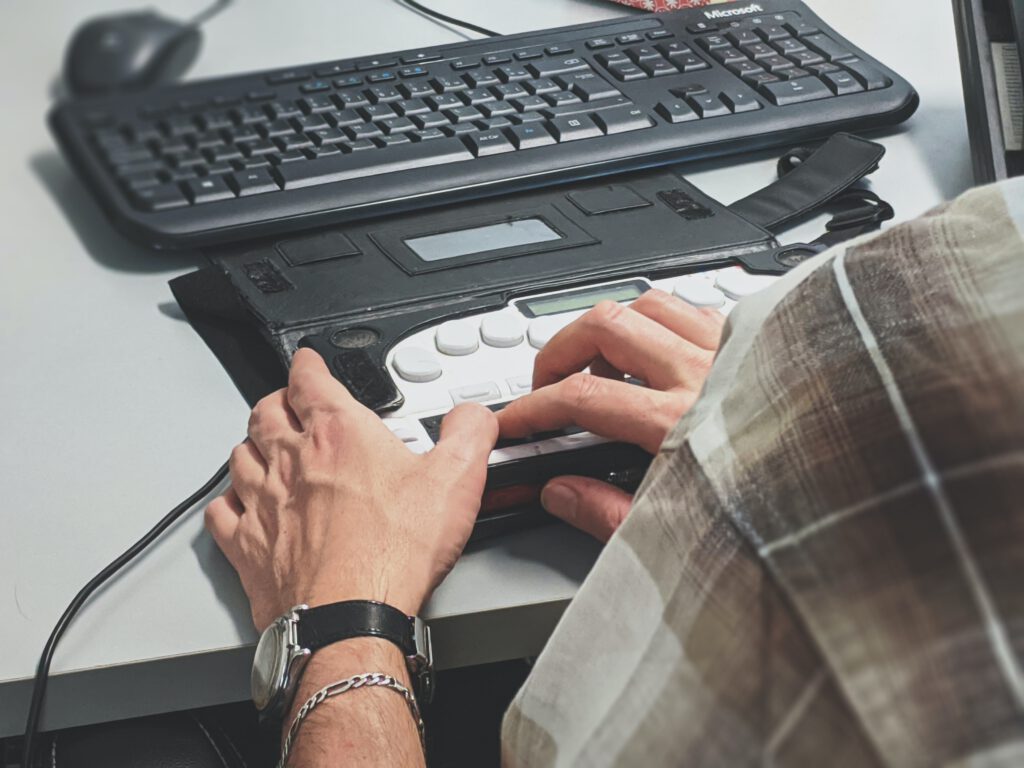 Tastatur und Braille-Reader mit Händen einer Person sichtbar